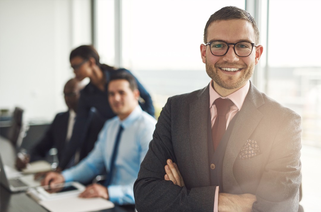 Photo of man in business suit with colleagues working on business outcomes