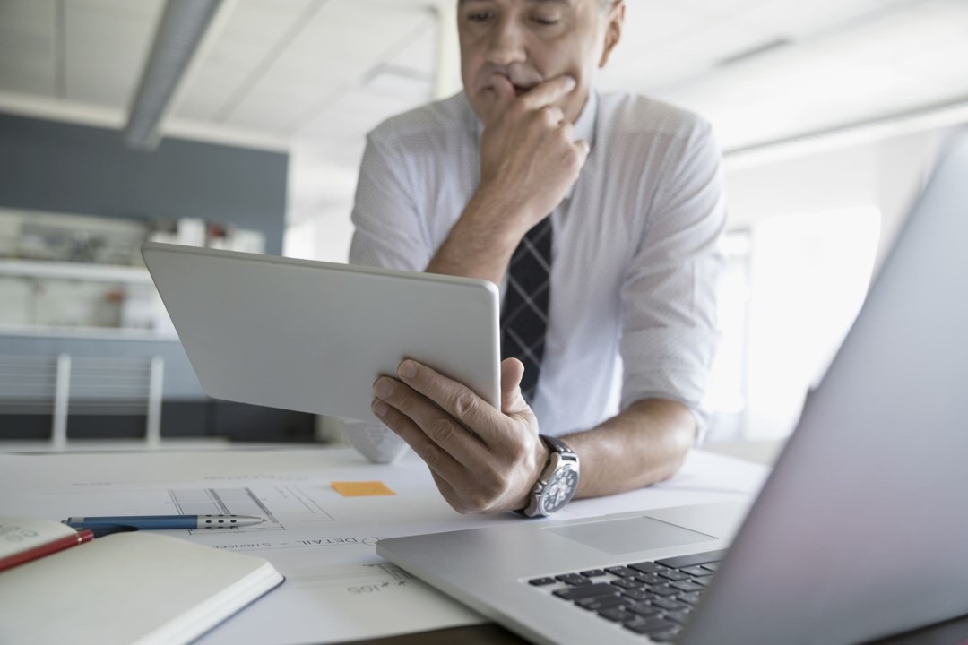 A businessman uses tablet and laptop to work