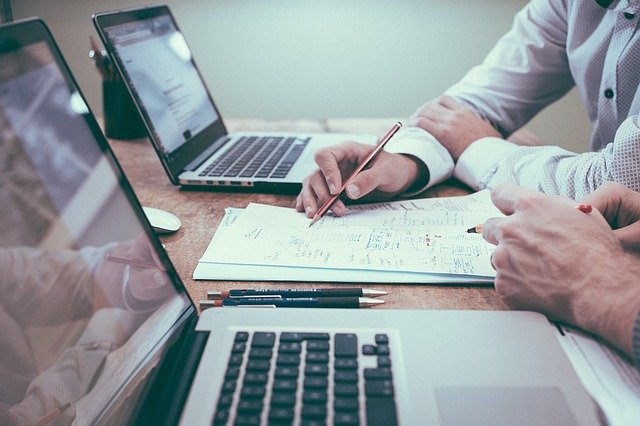 Two businessmen work together, facing their laptops, to determine moving Cisco Meraki licenses